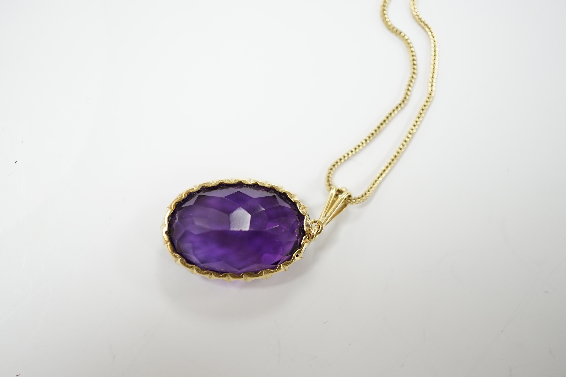 A yellow metal mounted single stone oval cut amethyst set pendant, 35mm, on a yellow metal chain, 48cm, gross weight 10.7 grams